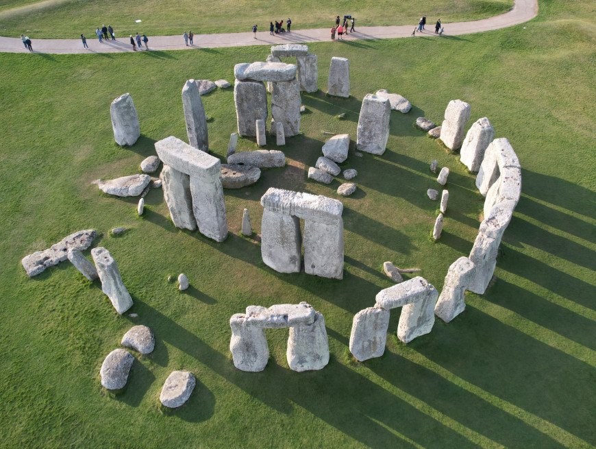 Stonehenge seen from above, with long shadows and a path where people are walking nearby.
